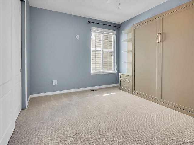 unfurnished bedroom featuring baseboards, visible vents, and light colored carpet