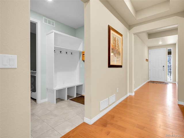 corridor featuring light wood-type flooring, visible vents, and baseboards