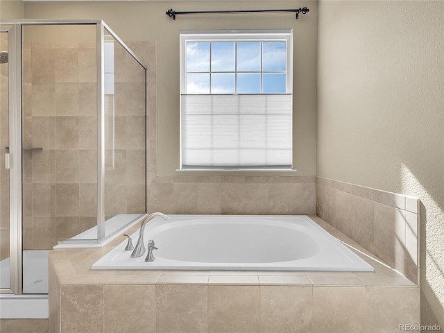 bathroom with a wealth of natural light, a garden tub, and a shower stall