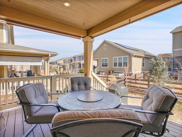 wooden terrace with a residential view, grilling area, and outdoor dining space