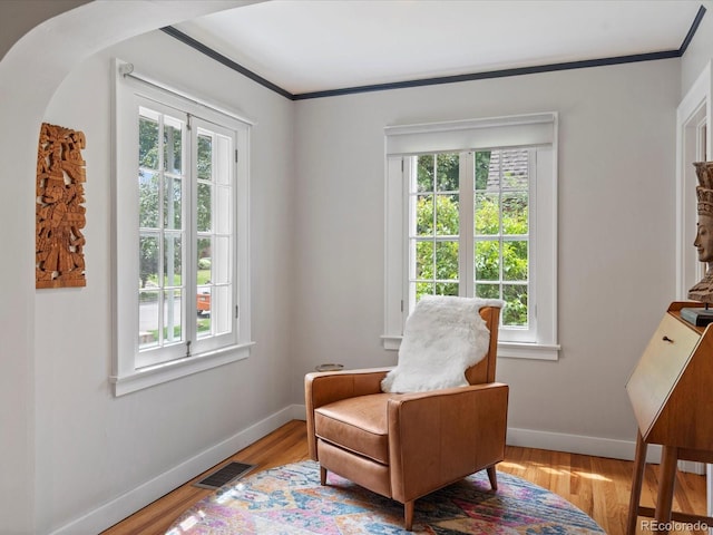 living area with ornamental molding and light wood-type flooring