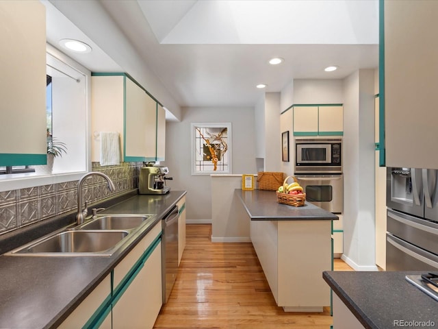 kitchen featuring appliances with stainless steel finishes, sink, light hardwood / wood-style flooring, a center island, and white cabinetry