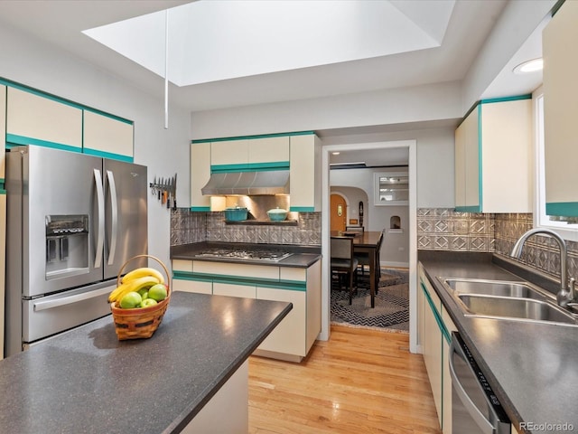 kitchen with appliances with stainless steel finishes, tasteful backsplash, sink, light hardwood / wood-style floors, and white cabinetry