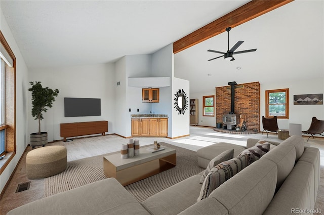 2100 Bibles Hill Dr, Franktown, CO 80116 - living area featuring a wood stove, a ceiling fan, beamed ceiling, high vaulted ceiling, and light wood-type flooring