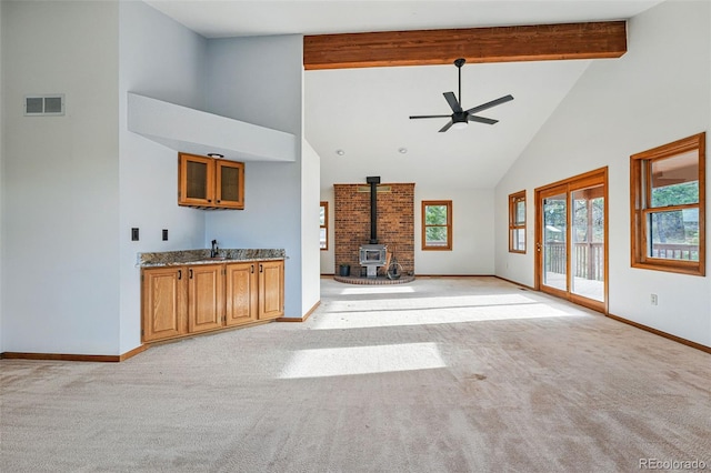 2100 Bibles Hill Dr, Franktown, CO 80116 - unfurnished living room with high vaulted ceiling, a wood stove, ceiling fan, baseboards, and light colored carpet