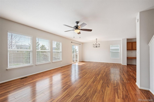 unfurnished living room with visible vents, baseboards, dark wood-style floors, and ceiling fan with notable chandelier