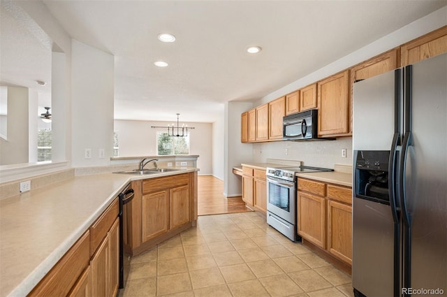 kitchen with light tile patterned floors, a sink, light countertops, a chandelier, and black appliances