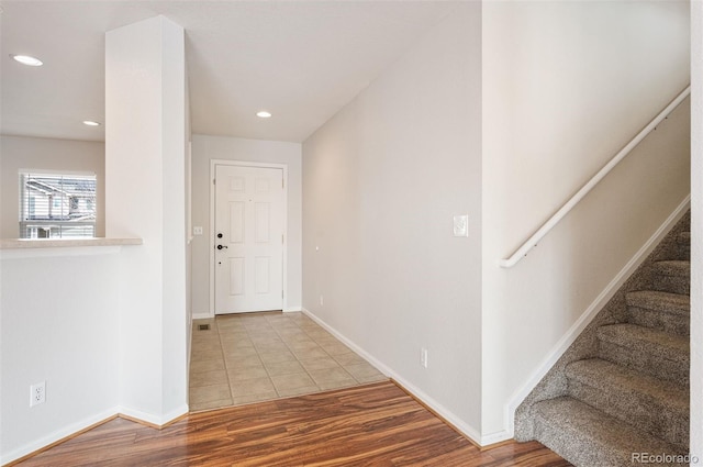 corridor with wood finished floors, recessed lighting, baseboards, and stairway