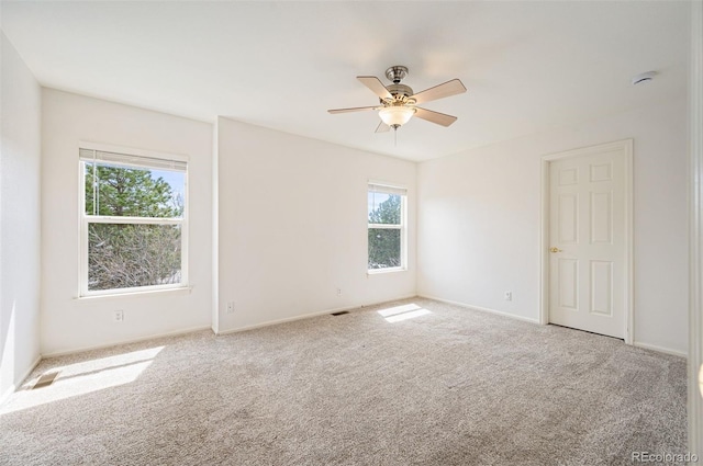 unfurnished room featuring baseboards, a ceiling fan, visible vents, and carpet floors