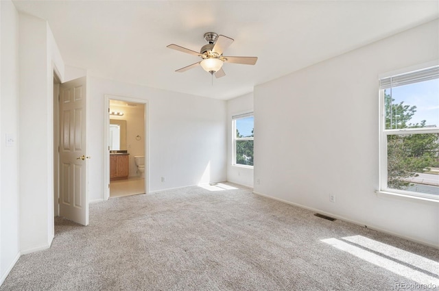 unfurnished room with baseboards, visible vents, light colored carpet, and a ceiling fan