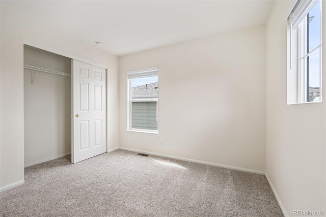 unfurnished bedroom with a closet, baseboards, carpet flooring, and visible vents