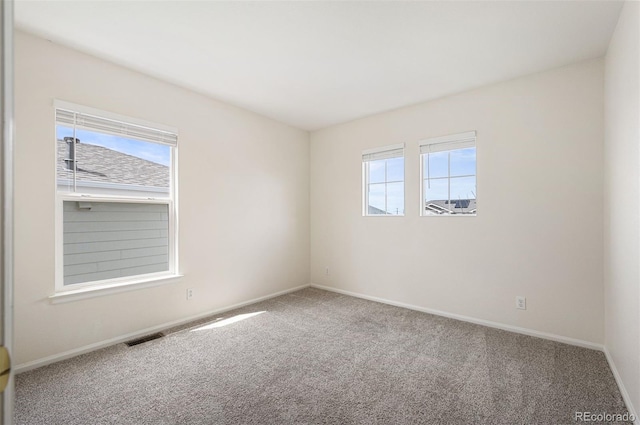 spare room with visible vents, baseboards, plenty of natural light, and carpet