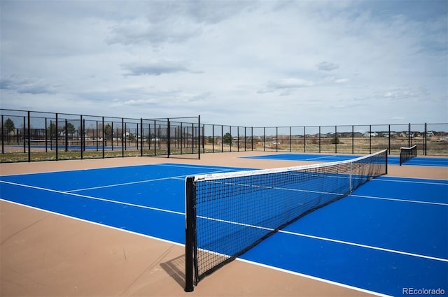 view of tennis court featuring fence and community basketball court
