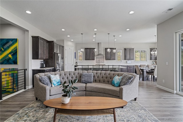 living area featuring baseboards, recessed lighting, light wood-style flooring, and a notable chandelier