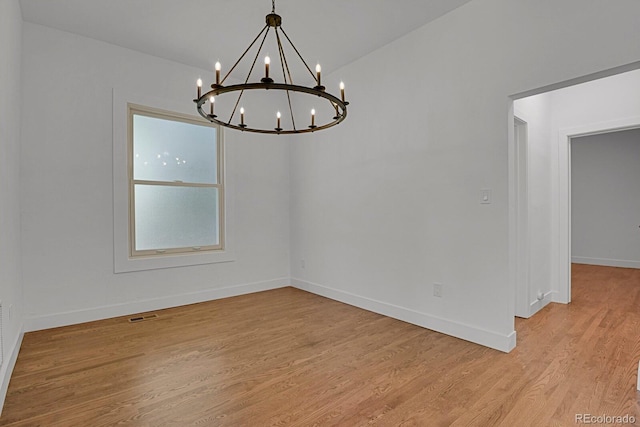 unfurnished room featuring vaulted ceiling, a notable chandelier, and light hardwood / wood-style floors