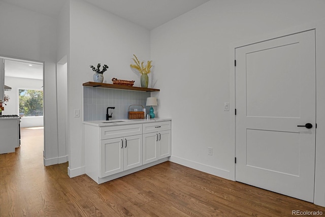 interior space with light wood-type flooring, white cabinetry, and sink