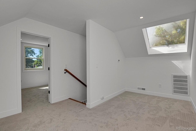 bonus room featuring light carpet and vaulted ceiling with skylight