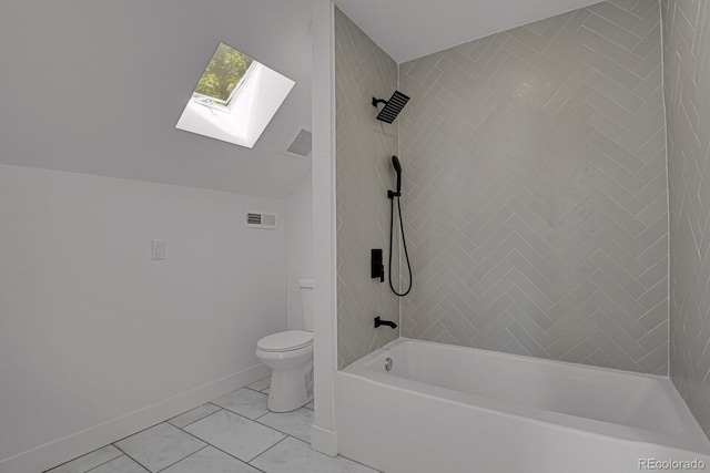 bathroom featuring lofted ceiling with skylight, toilet, and tiled shower / bath