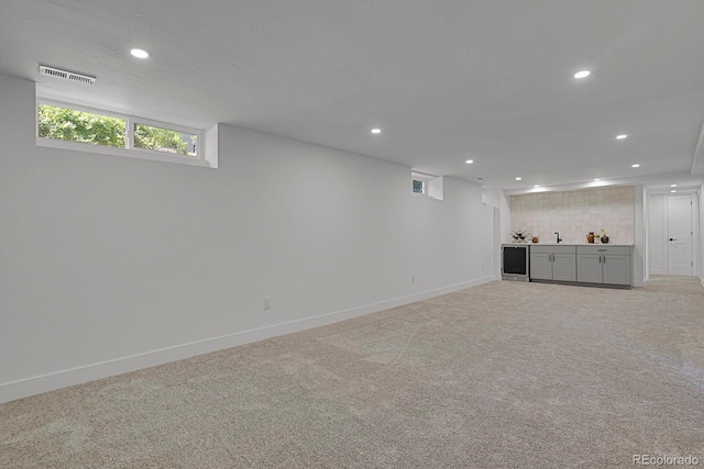 basement featuring wine cooler and light colored carpet