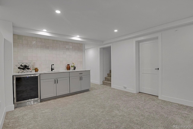 bar featuring gray cabinets, tasteful backsplash, sink, beverage cooler, and light colored carpet