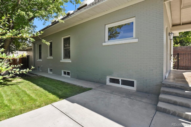 view of side of home featuring a lawn and a patio area