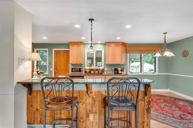 1161 S Johnson Way, Lakewood, CO 80232 - kitchen with stainless steel microwave, a kitchen bar, healthy amount of natural light, dark stone counters, and recessed lighting
