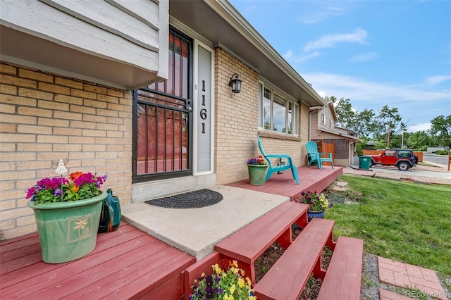 1161 S Johnson Way, Lakewood, CO 80232 - property entrance featuring brick siding, a lawn, and a wooden deck