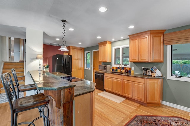 1161 S Johnson Way, Lakewood, CO 80232 - kitchen featuring black appliances, light wood-style flooring, a kitchen bar, dark stone countertops, and recessed lighting