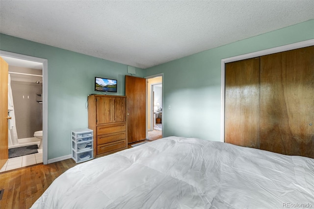1161 S Johnson Way, Lakewood, CO 80232 - bedroom featuring a closet, wood finished floors, a textured ceiling, and connected bathroom