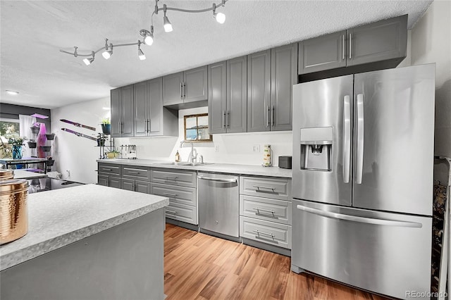 1711 Cato Cir Unit 21, Lafayette, CO 80026 - kitchen featuring appliances with stainless steel finishes, gray cabinetry, light countertops, light wood finished floors, and a textured ceiling