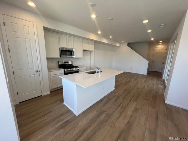 kitchen featuring white cabinetry, stainless steel appliances, dark wood-type flooring, and an island with sink