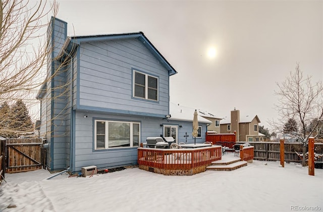 snow covered rear of property with a deck