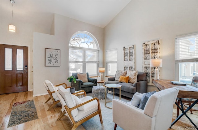 living room featuring plenty of natural light, light hardwood / wood-style floors, and high vaulted ceiling