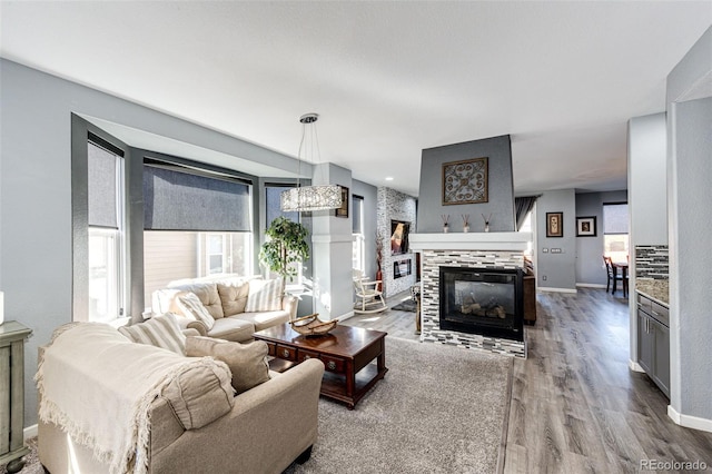 living room featuring a chandelier, light hardwood / wood-style floors, and a tile fireplace