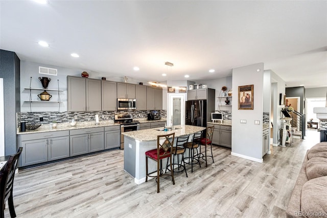 kitchen featuring sink, gray cabinets, a breakfast bar, appliances with stainless steel finishes, and decorative light fixtures