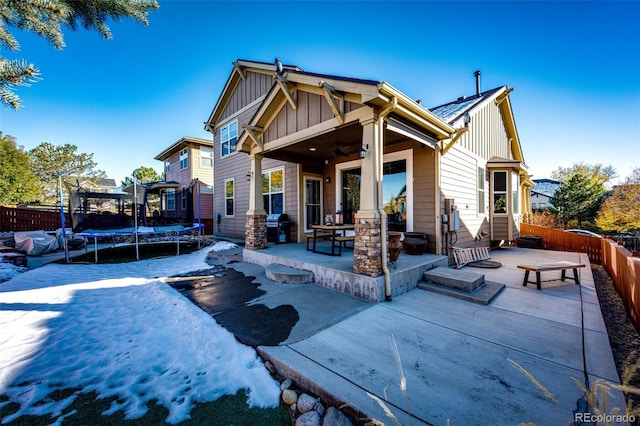 back of property with a trampoline and a patio area