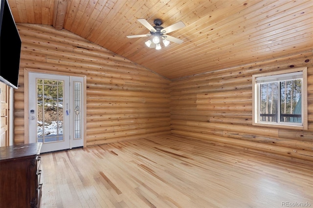 empty room featuring lofted ceiling, wood ceiling, rustic walls, ceiling fan, and light hardwood / wood-style flooring