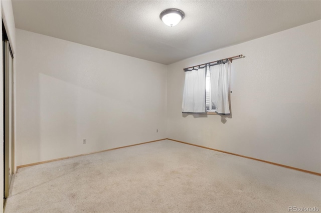 empty room with a textured ceiling and light colored carpet