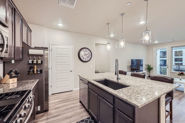 6153 N Ceylon St Unit 2-202, Denver, CO 80249 - kitchen featuring appliances with stainless steel finishes, light wood-type flooring, dark brown cabinetry, light stone countertops, and recessed lighting