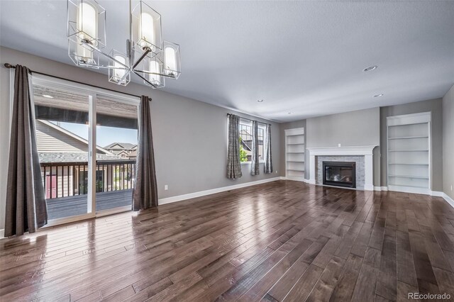 7720 S Queensburg Way, Aurora, CO 80016 - unfurnished living room with built in shelves, dark wood-type flooring, baseboards, and a chandelier