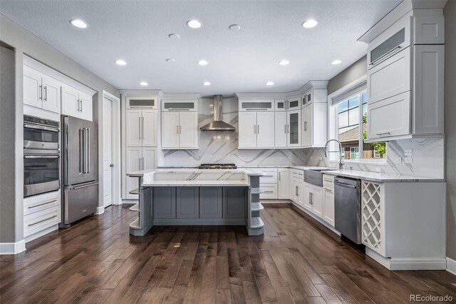 7720 S Queensburg Way, Aurora, CO 80016 - kitchen with appliances with stainless steel finishes, wall chimney range hood, a sink, recessed lighting, and dark wood finished floors