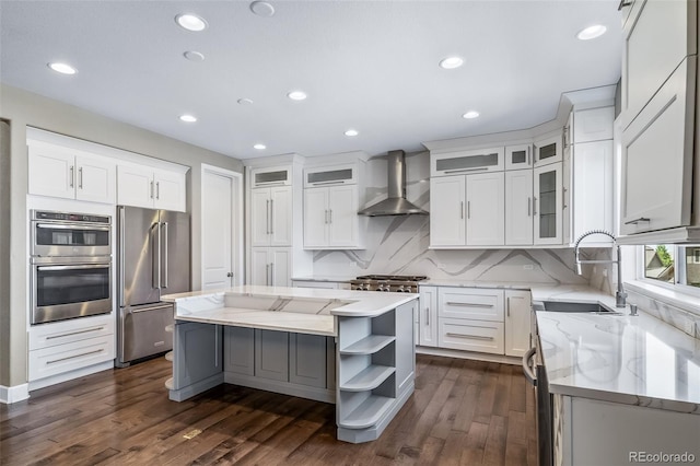7720 S Queensburg Way, Aurora, CO 80016 - kitchen featuring wall chimney exhaust hood, appliances with stainless steel finishes, a sink, a kitchen island, and white cabinetry