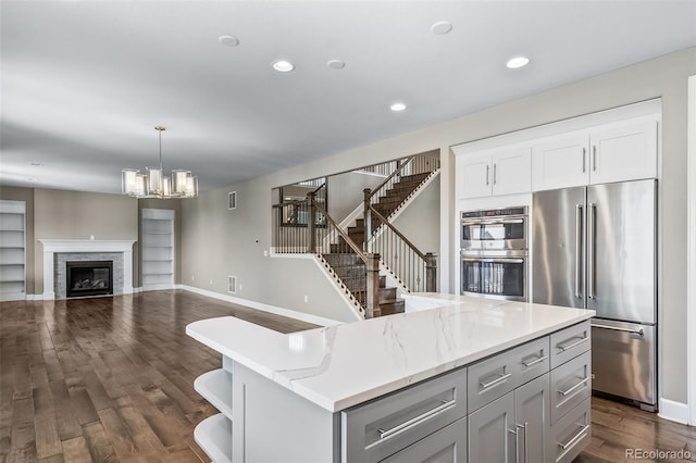 7720 S Queensburg Way, Aurora, CO 80016 - kitchen with appliances with stainless steel finishes, a center island, a chandelier, dark wood finished floors, and recessed lighting