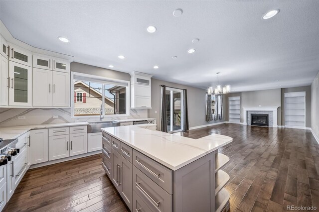 7720 S Queensburg Way, Aurora, CO 80016 - kitchen featuring a sink, open floor plan, dark wood-style floors, a kitchen island, and a chandelier
