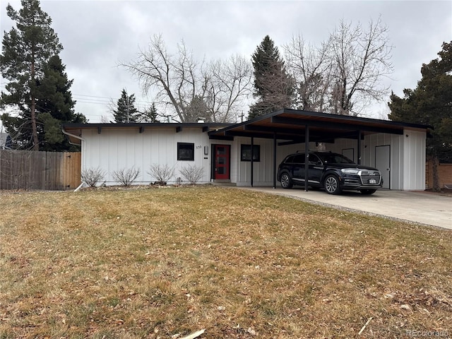 view of front of house with a carport, concrete driveway, fence, and a front lawn