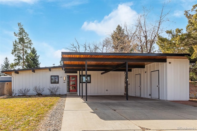 view of front of house with an attached carport, a front yard, board and batten siding, and driveway