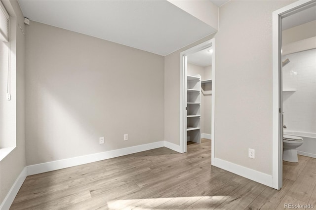 1615 Harlan St Unit 2, Lakewood, CO 80214 - unfurnished bedroom with wood finished floors, a spacious closet, baseboards, a closet, and ensuite bath