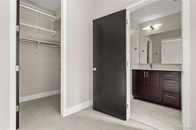 1615 Harlan St Unit 2, Lakewood, CO 80214 - bathroom featuring vanity, a spacious closet, baseboards, and carpet flooring