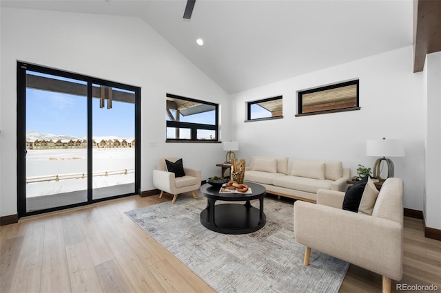 living area featuring ceiling fan, wood finished floors, baseboards, and high vaulted ceiling