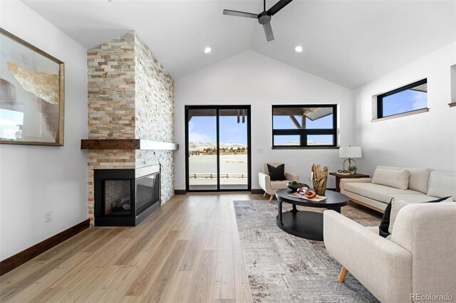 living room with baseboards, a fireplace, light wood-style floors, high vaulted ceiling, and a ceiling fan